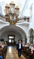 Pavel Svoboda kráčí k děkování, za ním na kůru jsou historické barokní varhany.